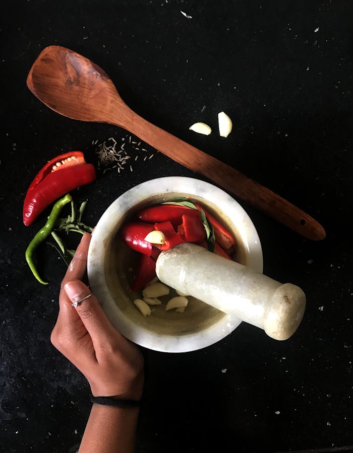 Spicy ingredients including chili peppers, garlic, and spices in a mortar for food preparation.