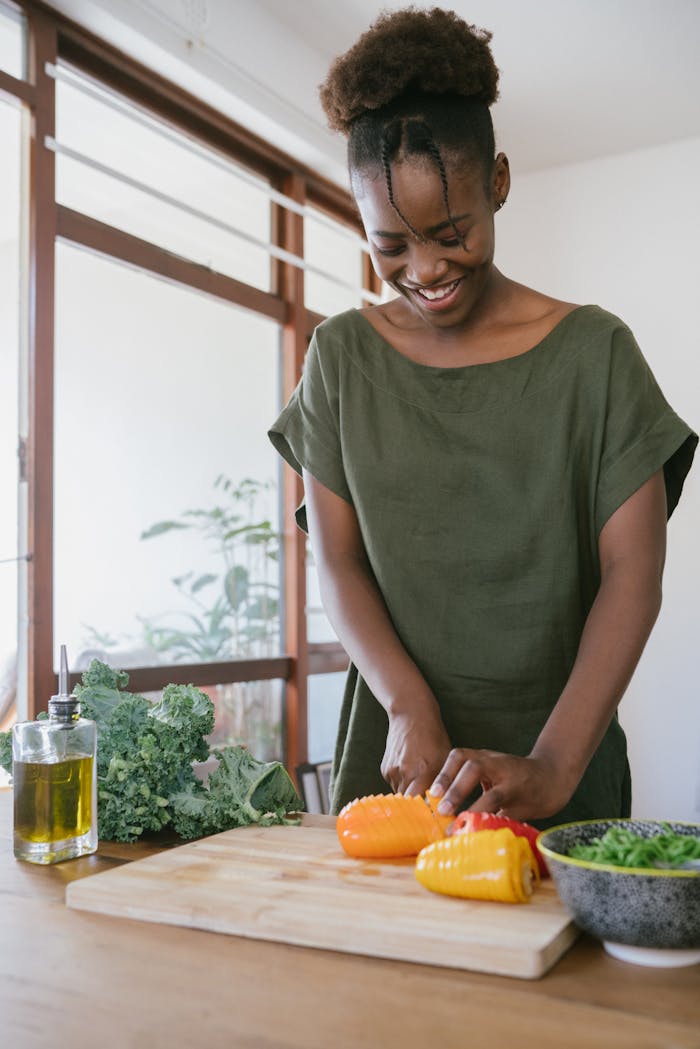 Smiling woman in kitchen slicing bell peppers, promoting healthy eating and joy in food preparation.